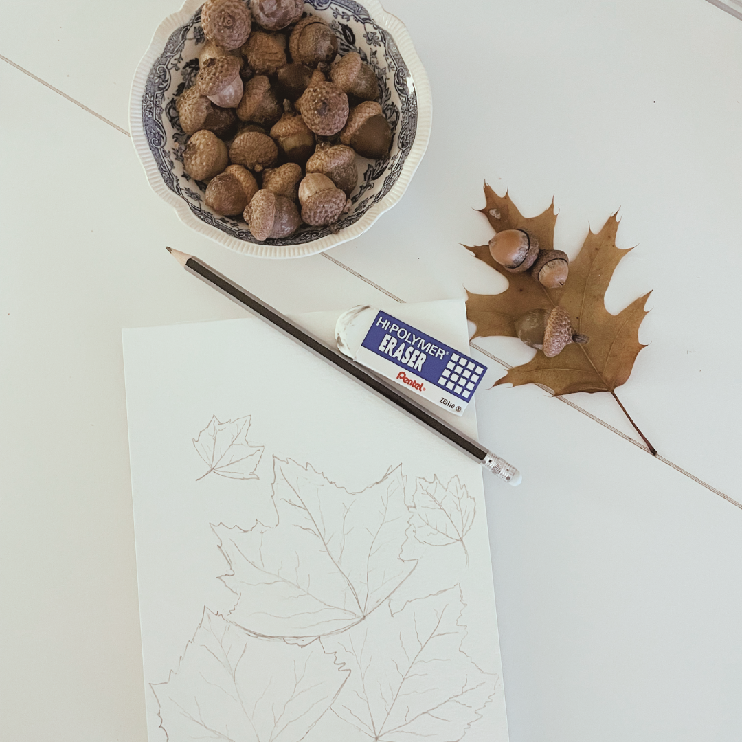 Autumn leaf sketches with a pencil, eraser, oak leaves, and a bowl of acorns