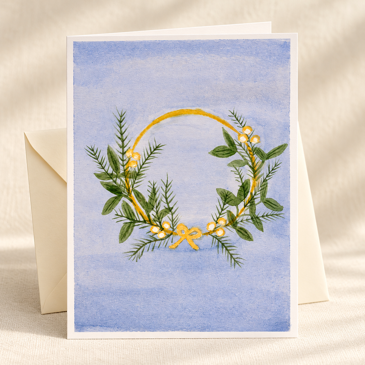 Winter Blue Wreath watercolor greeting card with an ivory envelope on a clean ivory background — artwork preview, not yet printed